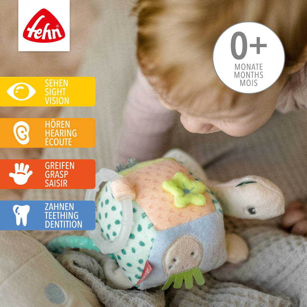 Baby spielt mit Baby Activity-Schildkröte aus weichem Plüsch