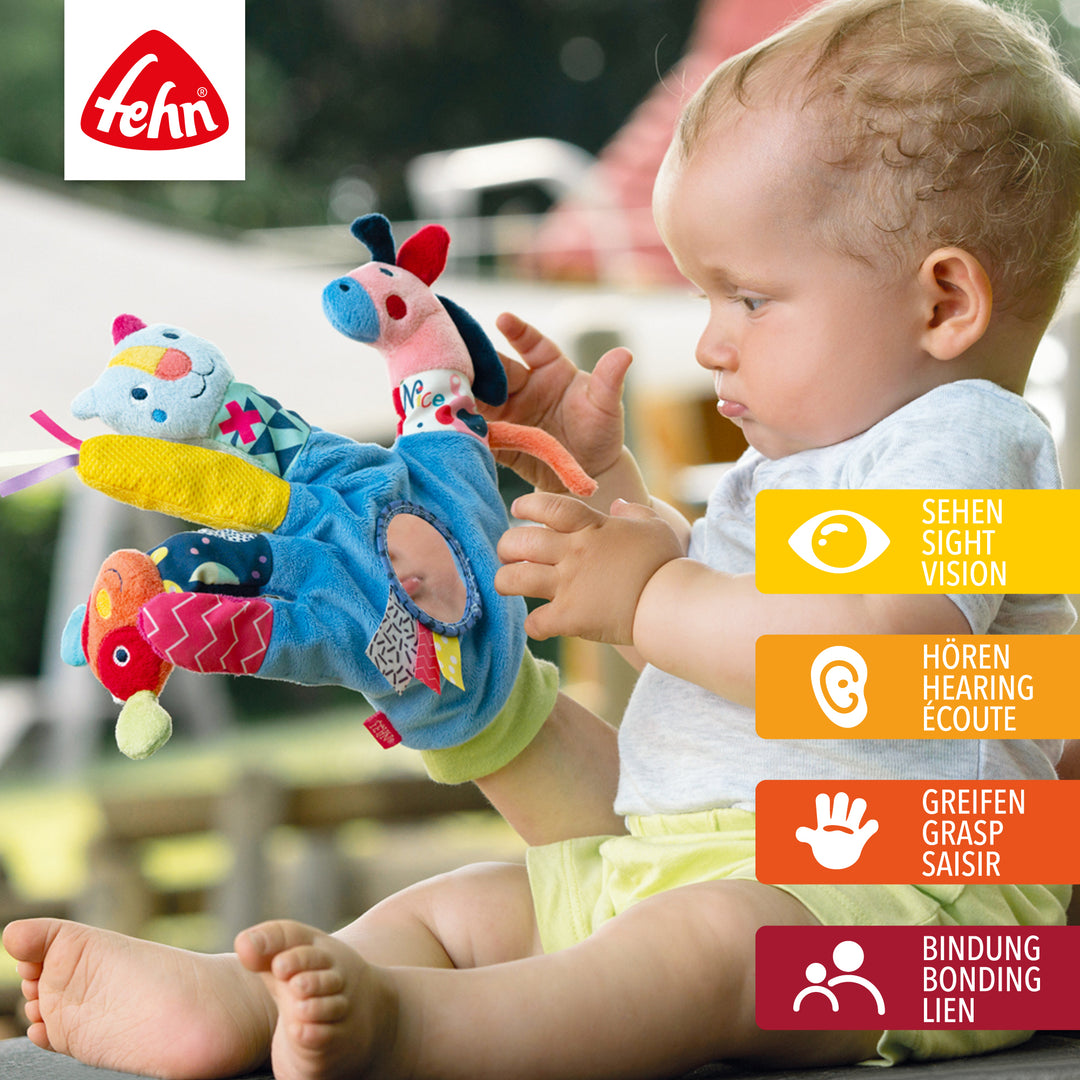 Baby greift nach Baby Spielhandschuh COLOR Friends aus weichem Plüsch