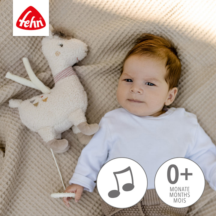Baby spielt liegend mit Baby Spieluhr Lama