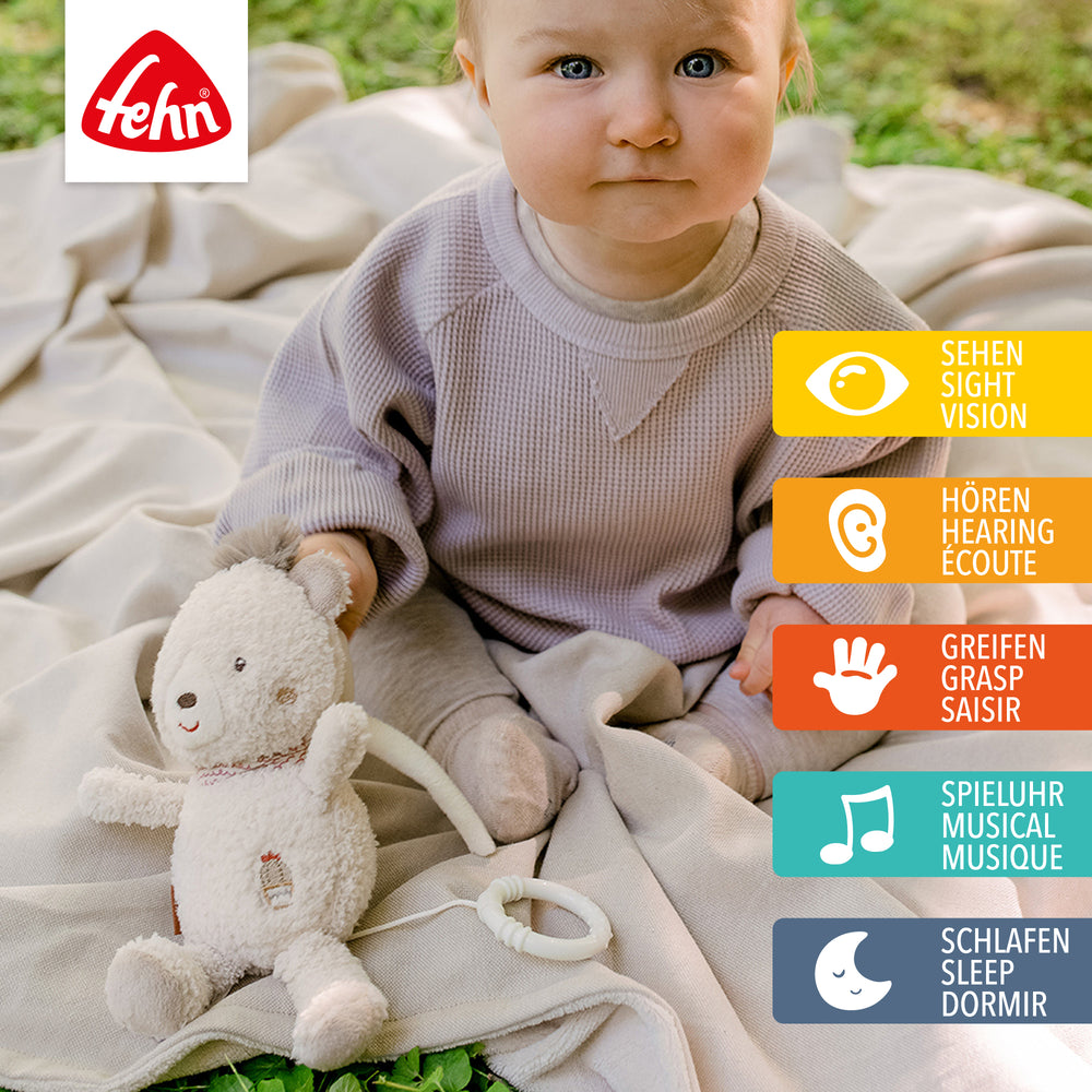 Baby spielt sitzend mit Baby Spieluhr Bär