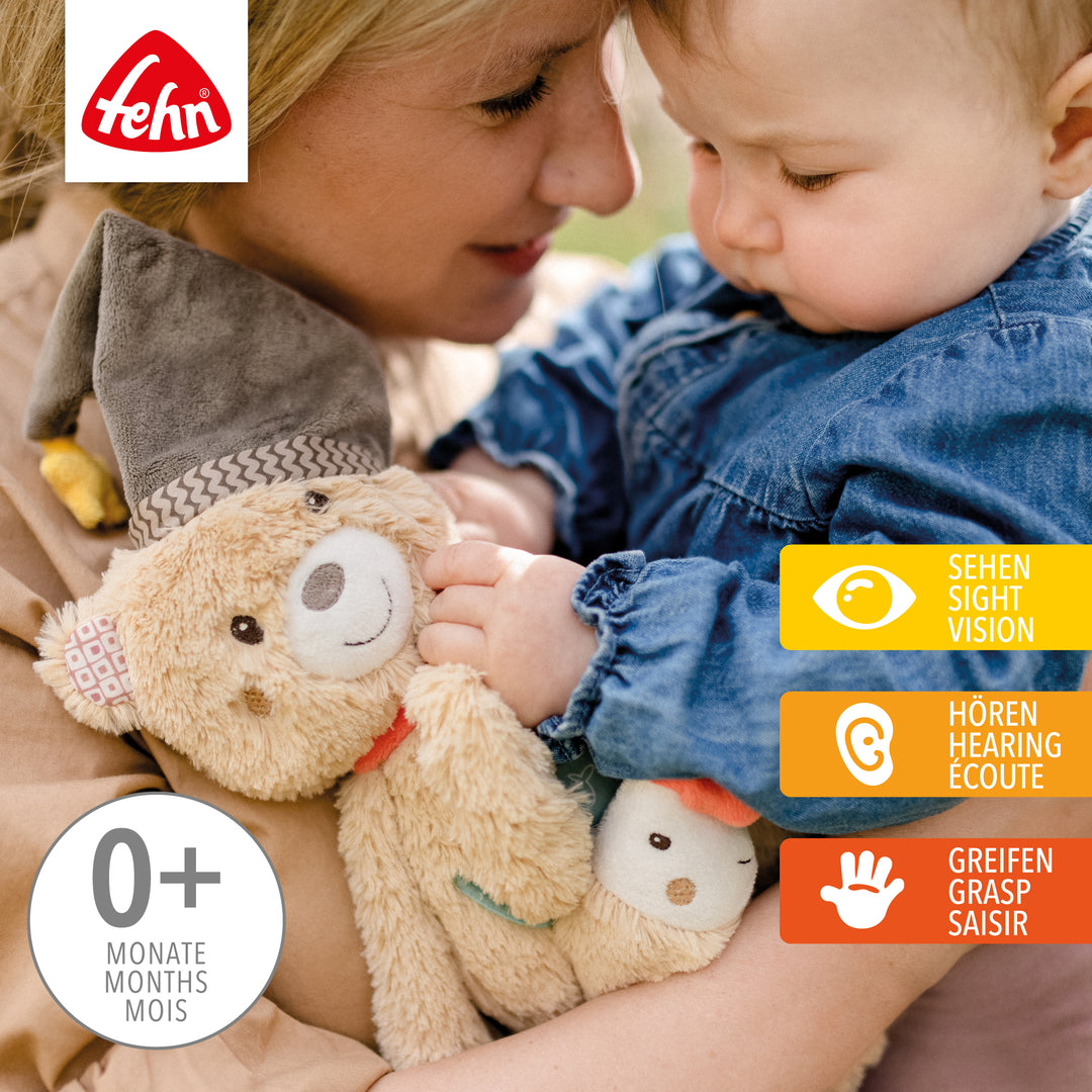 Baby spielt mit Baby Activity-Bär aus weichem Plüsch