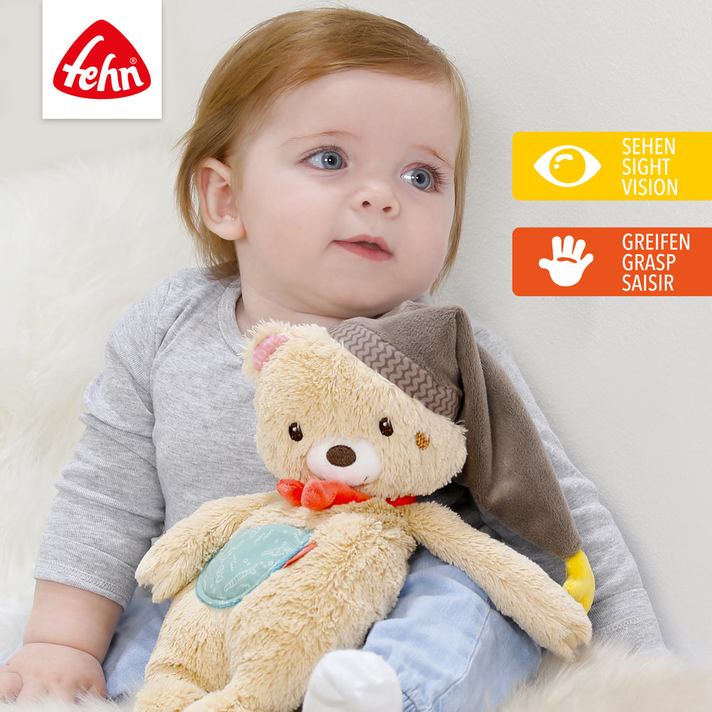 Baby spielt mit Baby Kuscheltier Bär