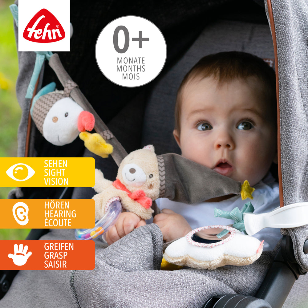 Baby spielt mit Baby Kinderwagenkette Bruno aus weichem Plüsch