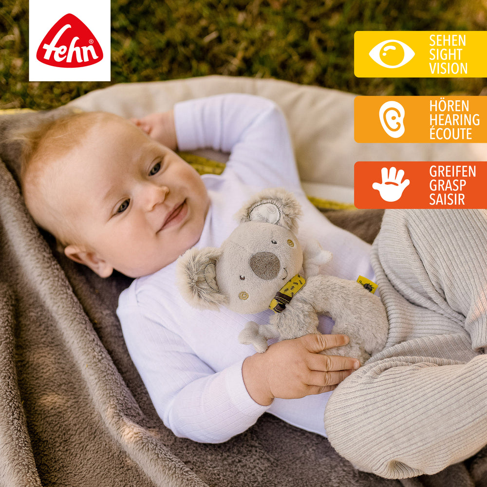 Baby spielt mit Plüsch-Ring-Greifling Koala