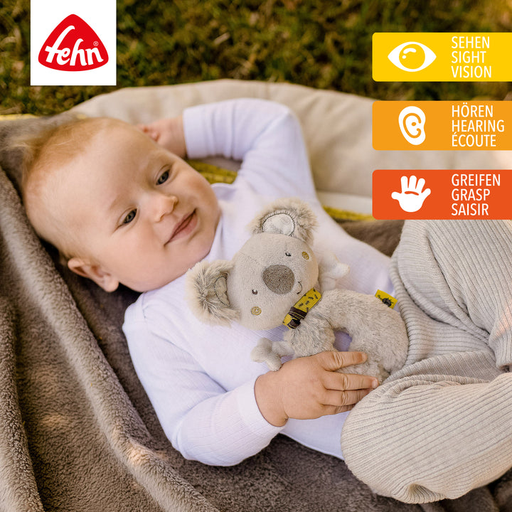 Baby spielt mit Plüsch-Ring-Greifling Koala