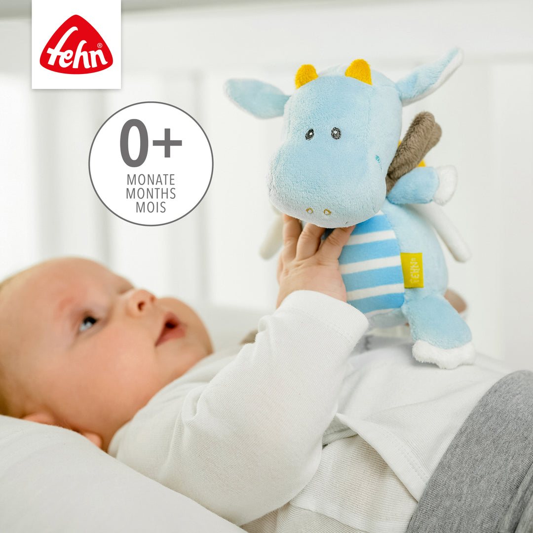 Baby spielt liegend mit Baby Spieluhr Drache