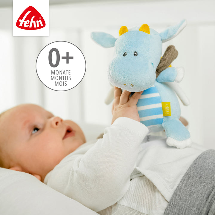 Baby spielt liegend mit Baby Spieluhr Drache