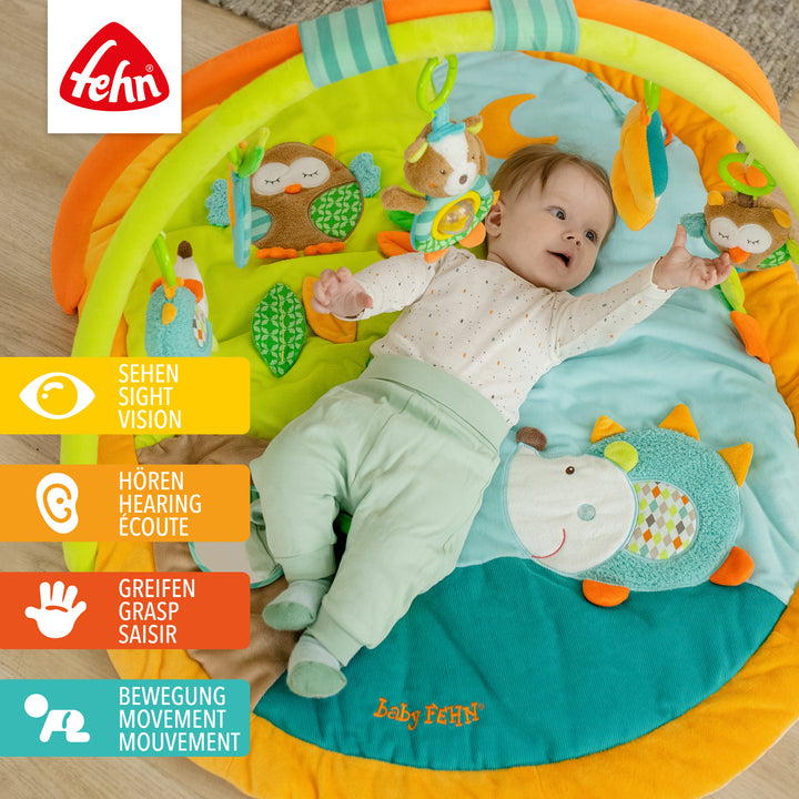 Baby liegt in Baby 3-D-Activity-Decke Forest und greift nach Spielelement
