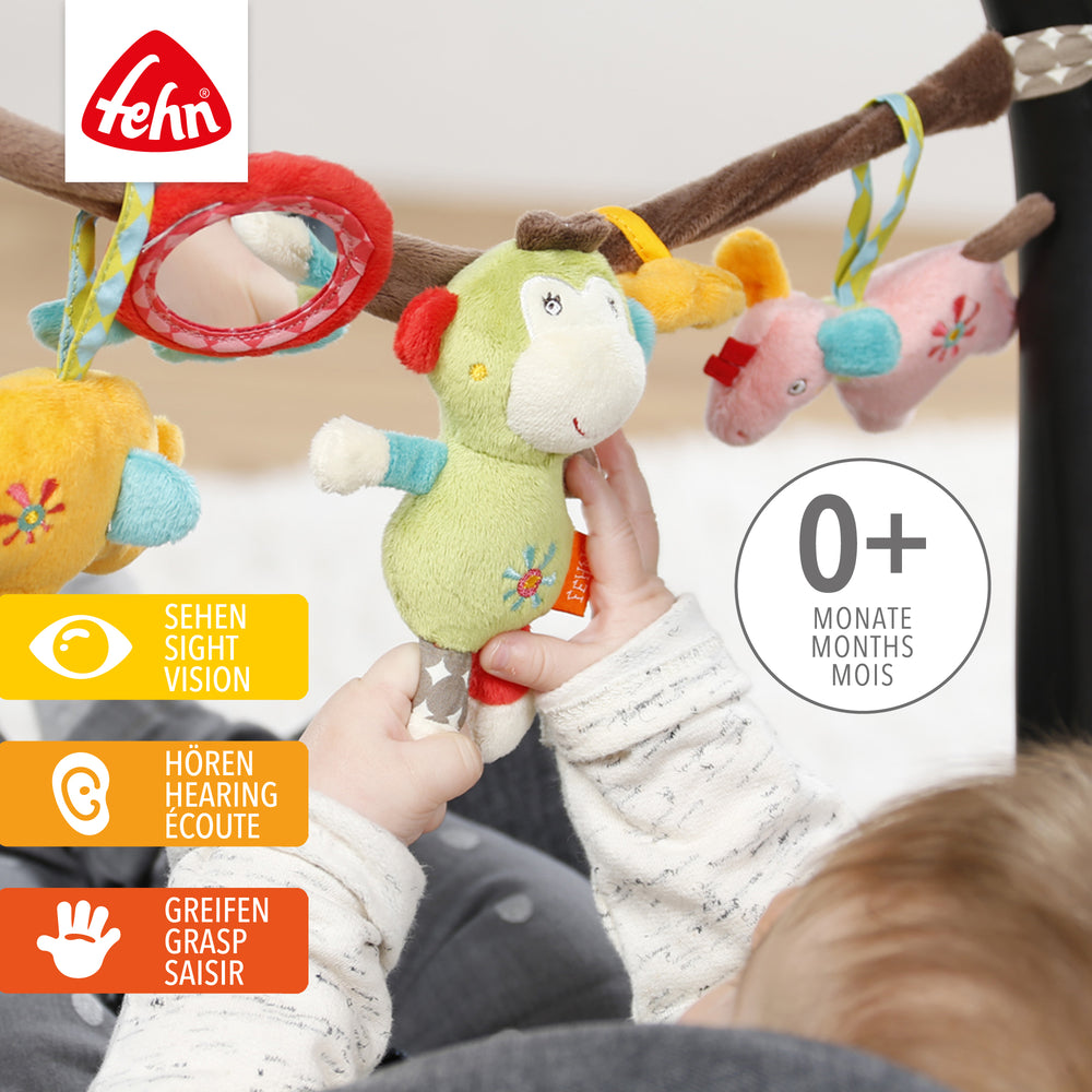 Baby greift nach Baby Kinderwagenkette Safari aus weichem Plüsch