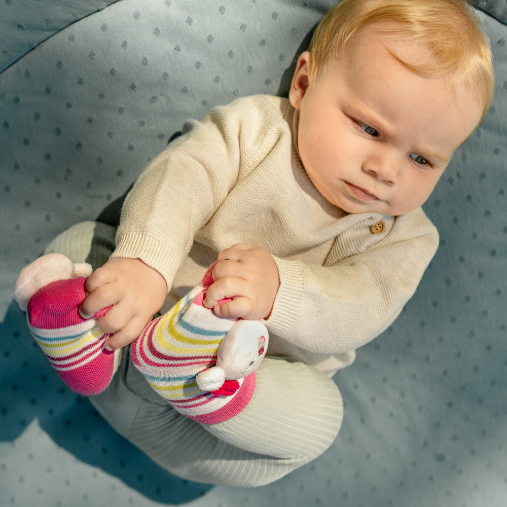 Baby greift nach Baby Rasselsocken Rehkitz