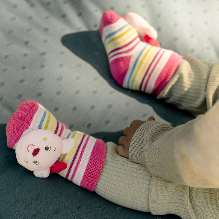Baby trägt Baby Rasselsocken Rehkitz an den Füßen