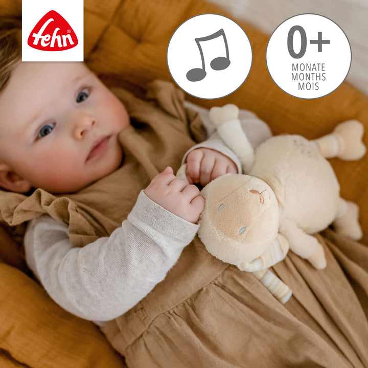 Baby spielt liegend mit Baby Spieluhr Schaf