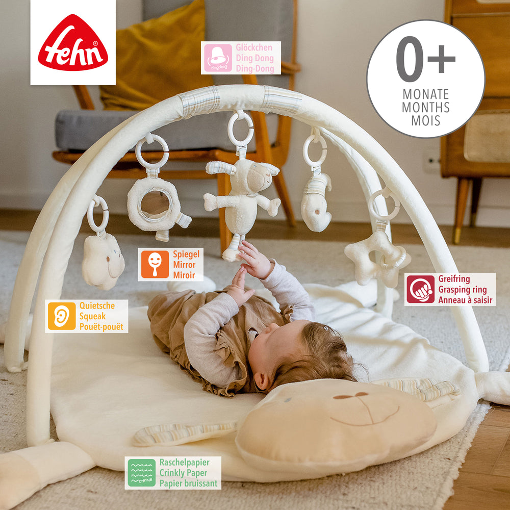 Baby liegt in Baby 3-D-Activity-Decke Schaf und greift nach Spielelement