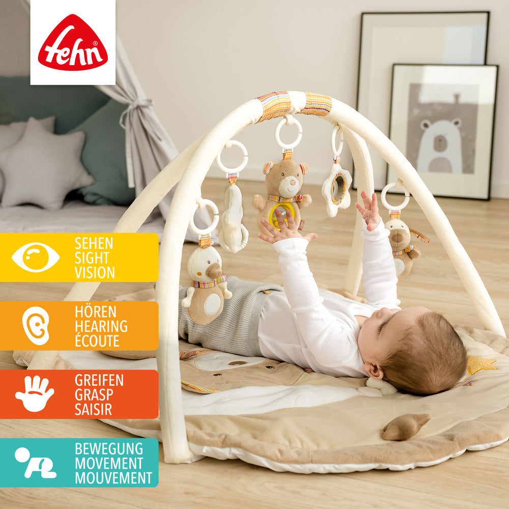 Baby liegt in Baby 3-D-Activity-Decke Rainbow und greift nach Spielelement